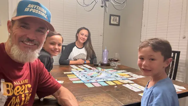 Mickey Moore, his wife and two sons - aged 7 and 10 - sit around a game of Monopoly