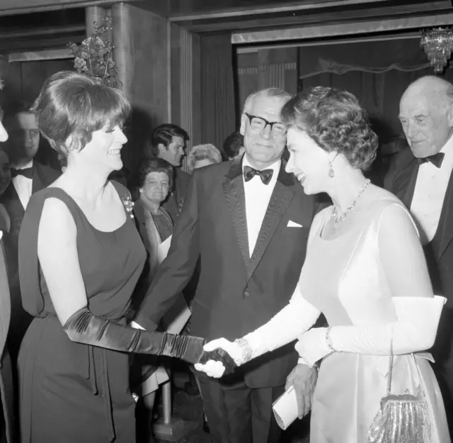 Maggie Smith Shaking hands with Queen Elizaebeth the second, Laurence Olivier is in the background smiling