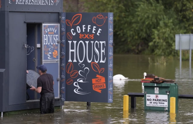 A man moves furniture out of flood water in Wellingborough, Northamptonshire