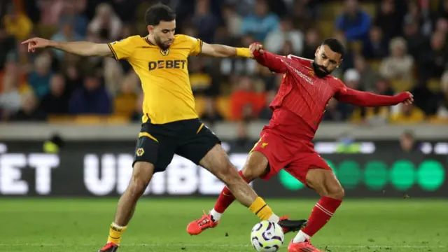 Rayan Ait-Nouri of Wolverhampton Wanderers battles for possession with Mohamed Salah of Liverpool during the Premier League match between Wolverhampton Wanderers FC and Liverpool FC at Molineux on September 28, 2024 in Wolverhampton, England.