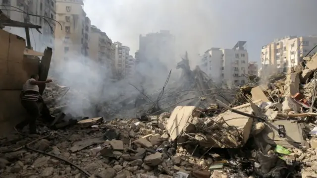 Rubble on the ground as smoke rises in the air