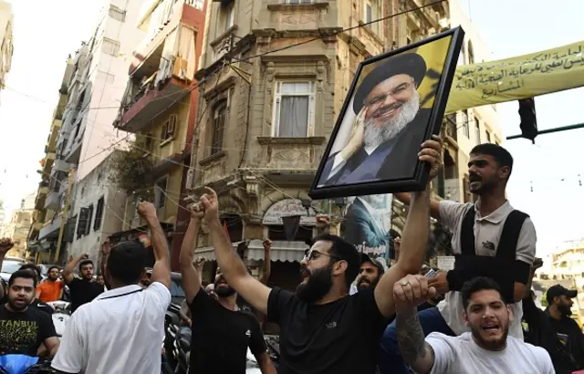 A man holds a poster of Hassan Nasrallah