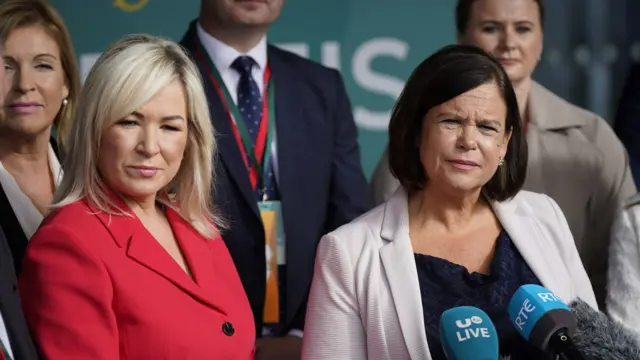 Michelle and Mary Lou McDonald together, Michelle in red and Mary in cream blazers.