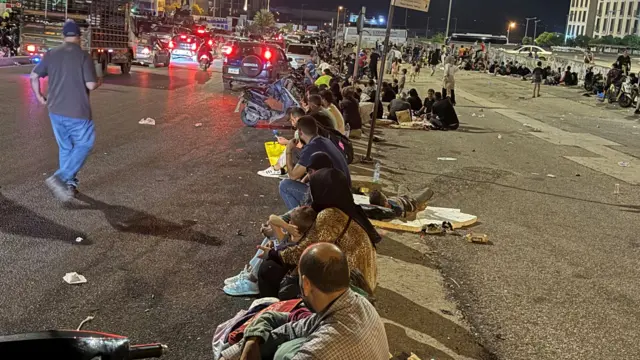 Displaced people sitting in a square at night in central Beirut