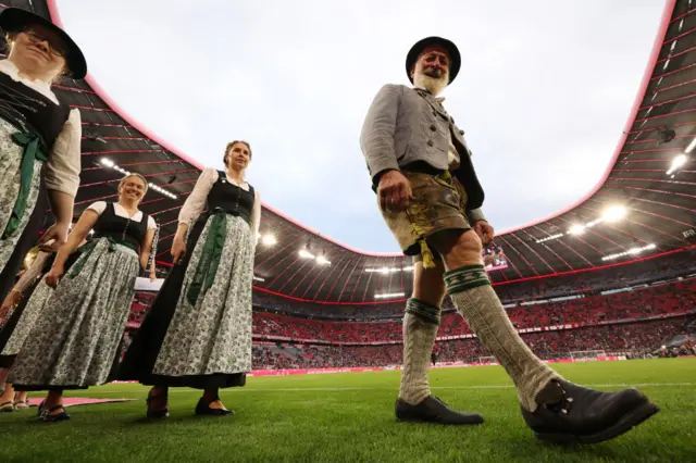 A man in lederhosen on the pitch at the Allianz Arena