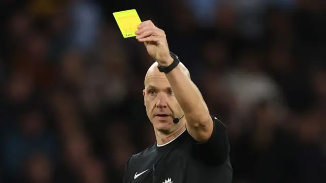 Referee Anthony Taylor shows a yellow card during the Premier League match between Wolverhampton Wanderers FC and Liverpool FC at Molineux on September 28, 2024 in Wolverhampton, England.