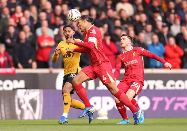 Virgil van Dijk of Liverpool headers the ball whilst under pressure from Matheus Cunha