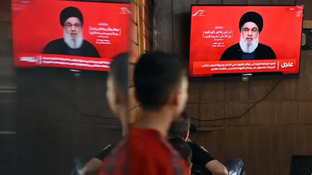 A screen shows Hezbollah leader Hassan Nasrallah addressing people in a televised address earlier this month