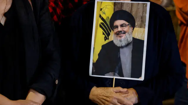 A person holds a photo of Nasrallah after his death was announced