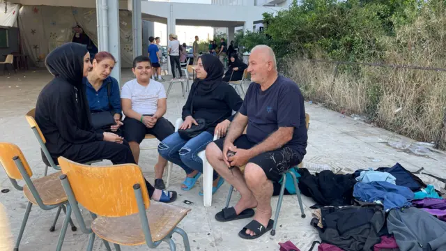 A family sit around on chairs