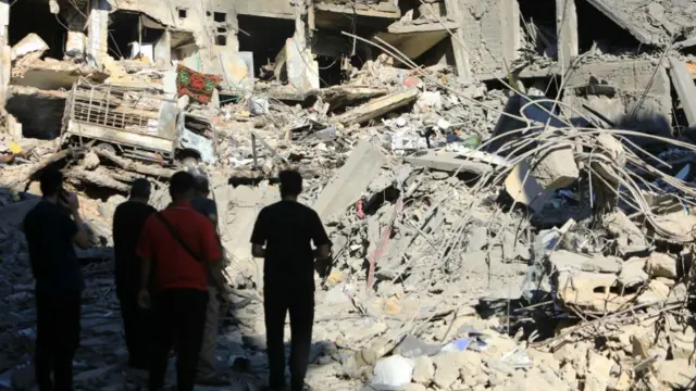 A group of people look on the rubble of a building after an air strike in the southern suburbs of Beirut