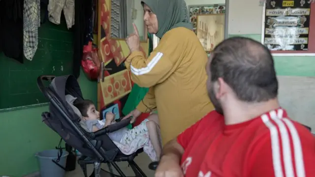 An elderly woman tends to a child in a pram