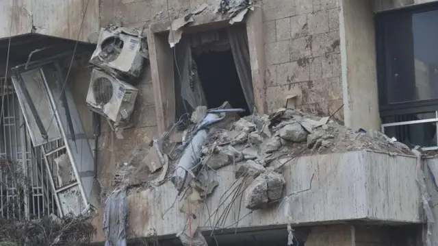 Close up showing part of a building after an air strike with piles of broken concrete and broken air conditioning units