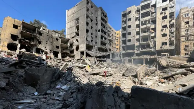 Foreground of image is of a flattened building with some buildings still standing in the distance