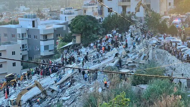 Rescuers search through the debris at the site of a strike on Ain El Delb