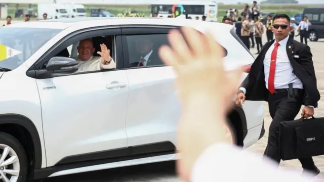 Pope Francis waves from a car after arriving at Soekarno-Hatta International Airport in Tangerang near Jakarta