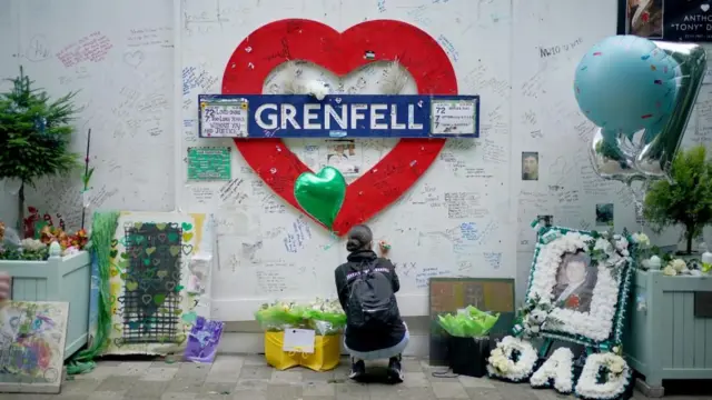 A member of the public at the memorial at the base of Grenfell Tower in London in remembrance of those who died in the Grenfell Tower fire