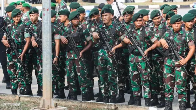 Military personnel hold their rifles as they stand guard ahead of the arrival of Pope Francis at Soekarno-Hatta International Airport on the outskirts of Jakarta on 3 September