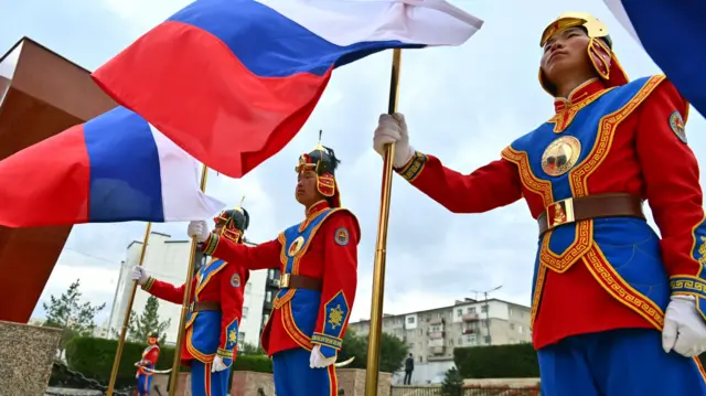 Mongolian servicemen of the honour guard company hold Russia's flag while dressed in uniform