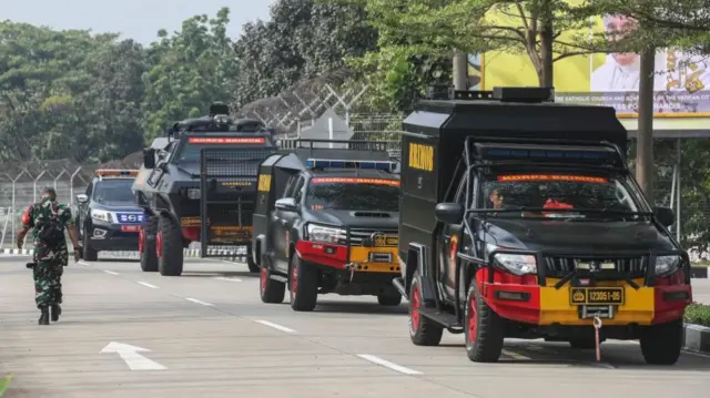 Military personnel walk near police armoured vehicles ahead of the arrival of Pope Francis at Soekarno-Hatta International Airport