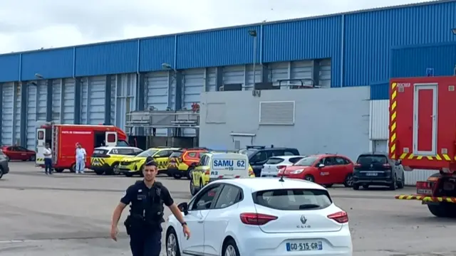 Ambulances and cars parked outside a warehouse at the port