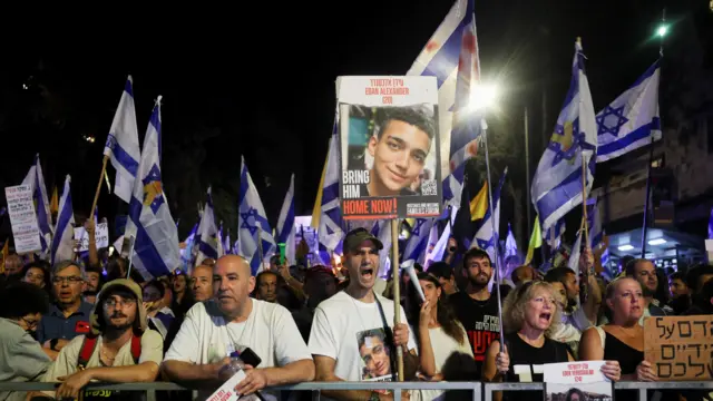 People attend a demonstration, holding Israeli flags and placards