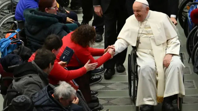 Pope Francis greets people on wheelchairs at Paul-VI hall in The Vatican in December 2023