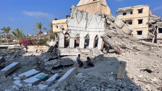 Palestinian children sit at the rubble of a mosque destroyed in an Israeli strike, amid the Israel-Hamas conflict, in Deir Al-Balah in the central Gaza Strip