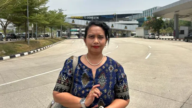 A woman standing outside an airport in a blue dress