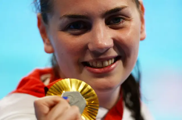 Tully Kearney holds up a Paralympic gold medal and smiles