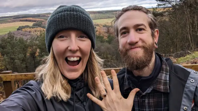 Chris Jamieson-Green and Sam Jamieson surrounded by nature as Sam holds hand up to show off engagement ring