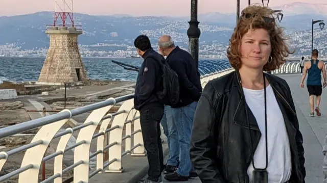 Victoria Lupton stands on a bridge with a mountain landscape in the background