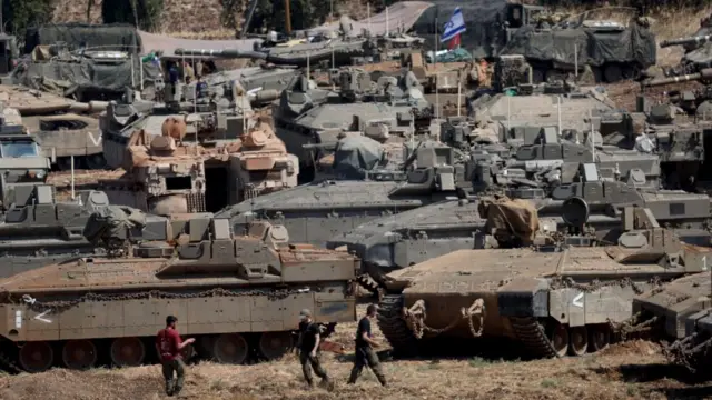 Israeli tanks mount on the Israel-Lebanon border, and Israeli flags can be seen waving on the tops of tanks