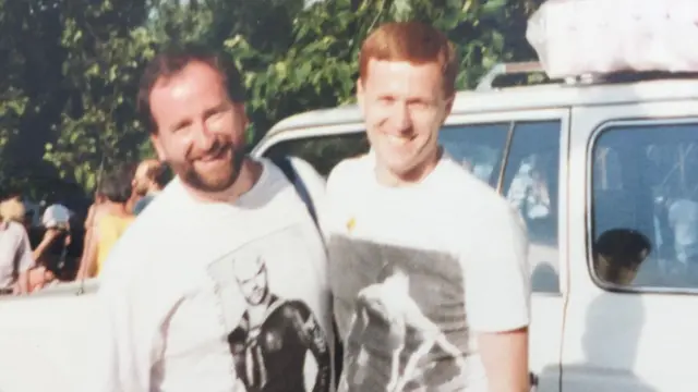 Andy Lambert and Mel Fawcus in white tshirts with white car behind them, both smiling