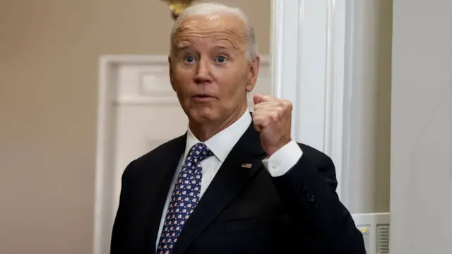 Biden gestures with his fist as he's asked questions by reporters in the White House