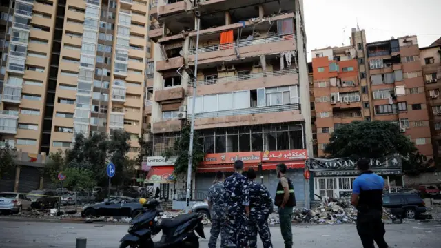 People gather in front of damaged building after air strike in Kola, Beirut