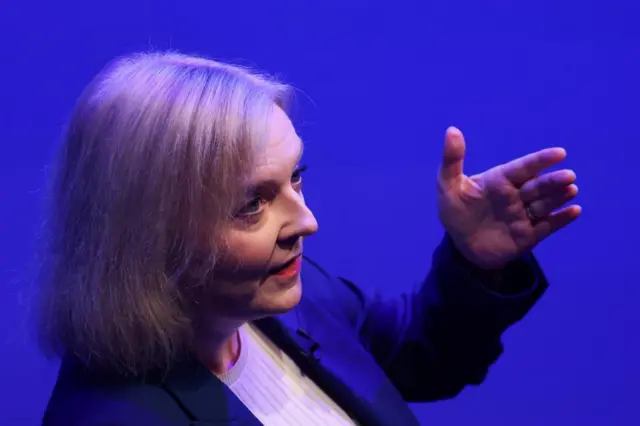 Liz Truss gestures as she speaks at an event