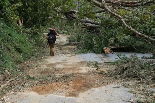 A man carries a chainsaw to help cut down trees and clear roads