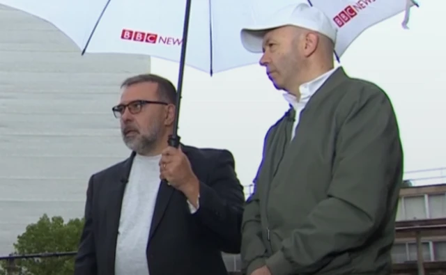 Two men standing under an umbrella