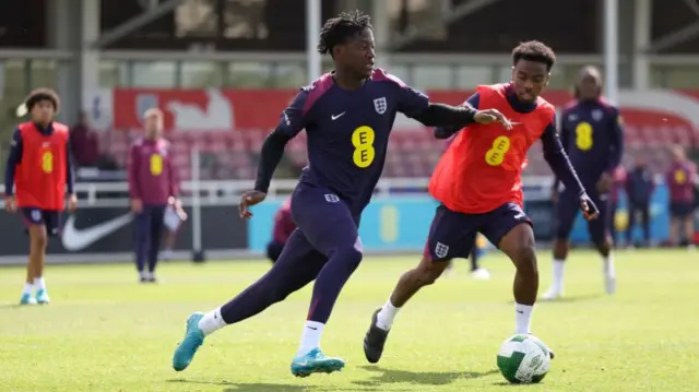 Kobbie Mainoo is tracked by Angel Gomes in training