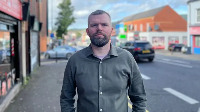 Gerry Carroll wearing a green shirt, he has brown hair and a brown beard