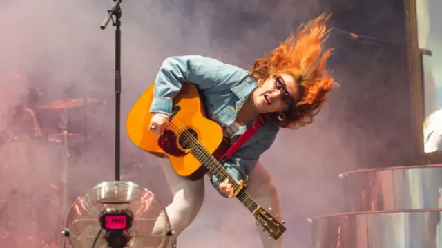 CMAT performing at Radio 1 Big Weekend, holding an acoustic guitar