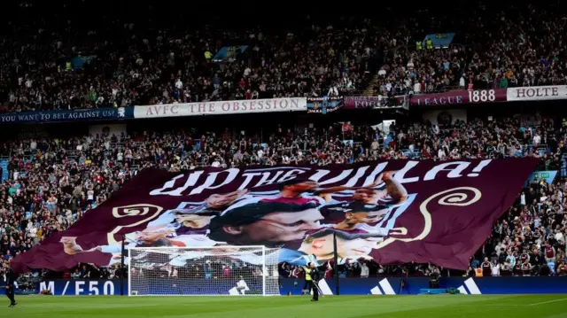 A banner saying 'Up the Villa' held up by fans during a Premier League match at Villa Park