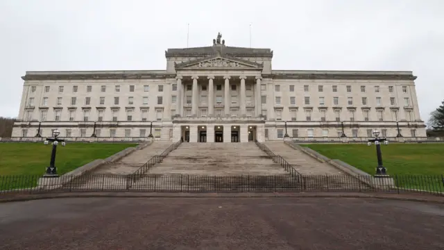 The exterior of Stormont Parliament Building - a large, white stone building with a staircase