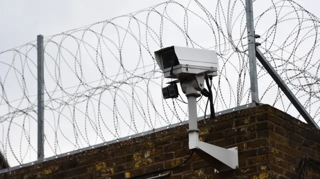 A stock photo of a surveillance camera on a prison wall