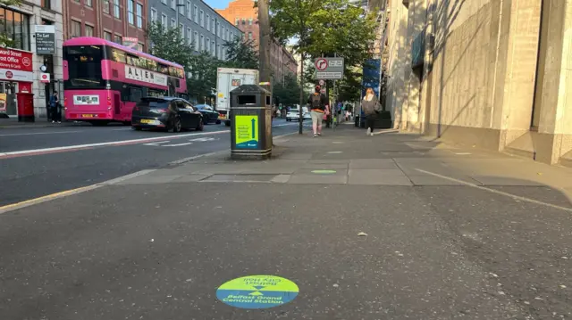 A view of a street in Belfast with a bin and stickers on the floor