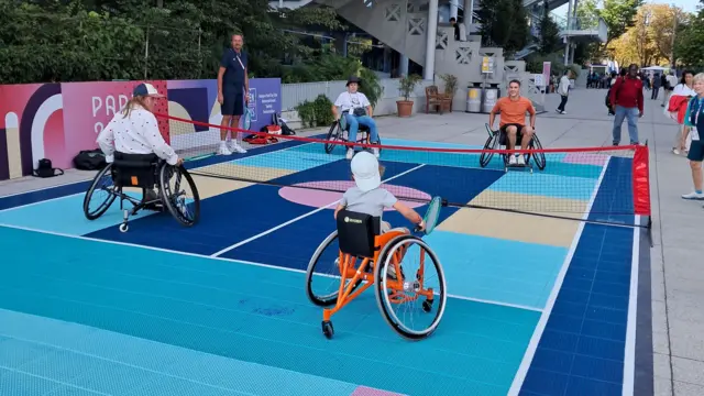 A family try wheelchair tennis outside Court Philippe Chatrier at Roland Garros