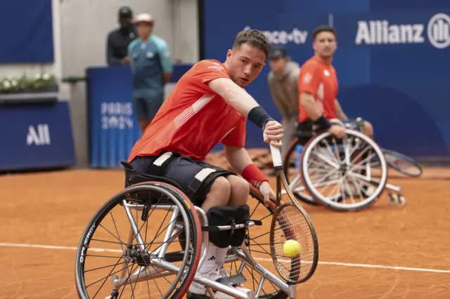 Alfie Hewett plays backhand in the wheelchair doubles at the Paralympics with partner Gordon Reid in the background