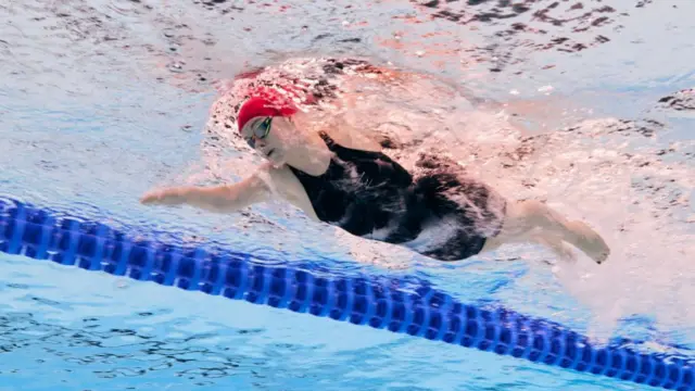 Maisie Summers-Newton swims with goggles under wear with the camera shot from underneath the water