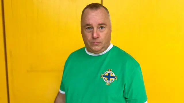 A man wearing a green Northern Ireland football top